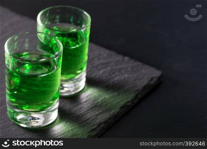 Two glasses of strong absinthe on a black background. Two glasses of strong absinthe