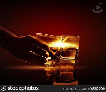 Two glasses of whiskey. Hand holding one of two glasses of whiskey with nature illustration in