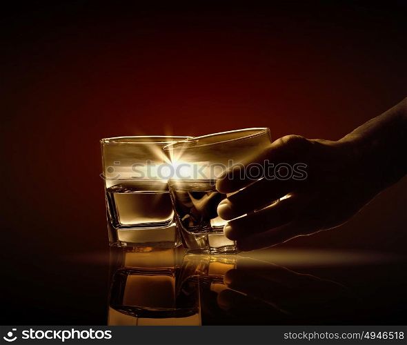 Two glasses of whiskey. Hand holding one of two glasses of whiskey with nature illustration in