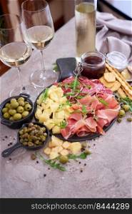 Two glasses of white wine and Italian antipasto meat platter on domestic kitchen.. Two glasses of white wine and Italian antipasto meat platter on domestic kitchen