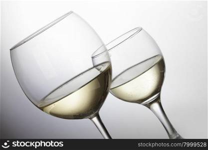 Two glasses of white wine over light grey background