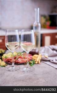 Two glasses of white wine with Italian antipasto meat platter on background.. Two glasses of white wine with Italian antipasto meat platter on background