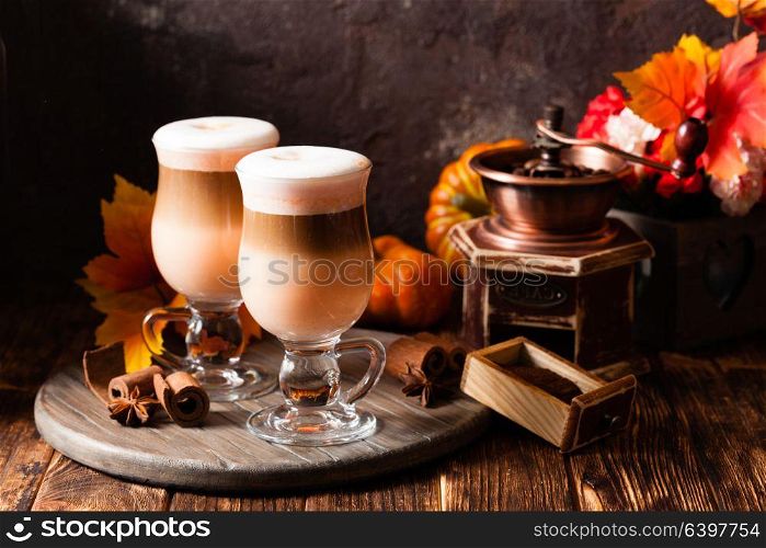 Two glasses pumpkin spicy latte with whipped cream and cinnamon on a wooden stand. Delicious pumpkin spicy latte