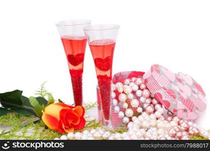 Two glasses, rose, colorful pearls necklaces and gift box on white background.