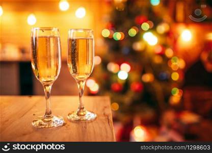 Two glasses with champagne,nobody, christmas decoration on background, blur effect. Xmas symbol to drink sparkling wine