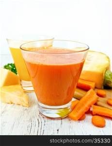 Two glassfuls juice of pumpkin and carrot, the vegetables on the background light wooden boards