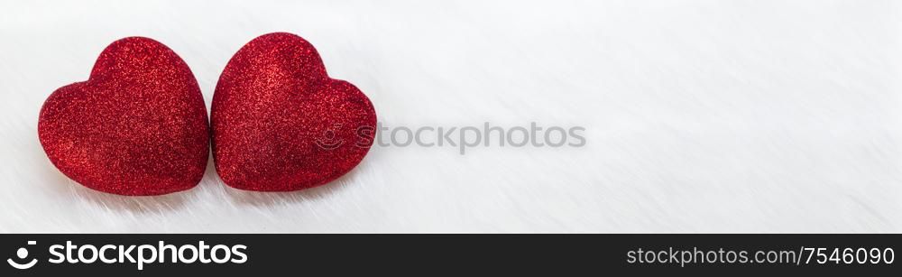 Two glitter hearts on white fur background with copy space for text. Two glitter hearts