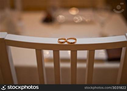 Two gold rings lie on a chair back.. Wedding rings on a chair back 709.