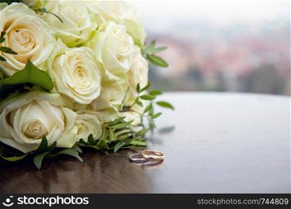 Two gold wedding rings on a round wooden table. Wedding in Prague.. Two gold wedding rings on a round wooden table