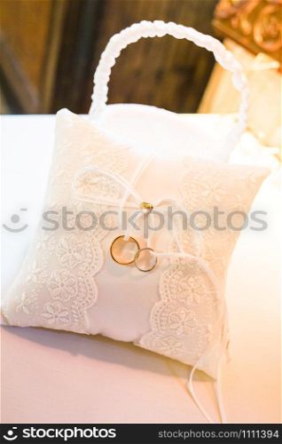 Two gold wedding rings on a white pillow close up. Two wedding rings on a white pillow close up