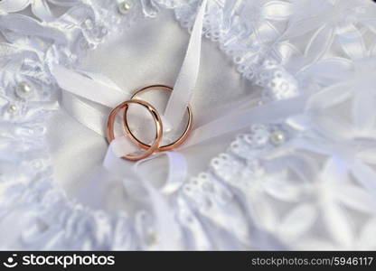 two gold wedding rings on bridal pillow