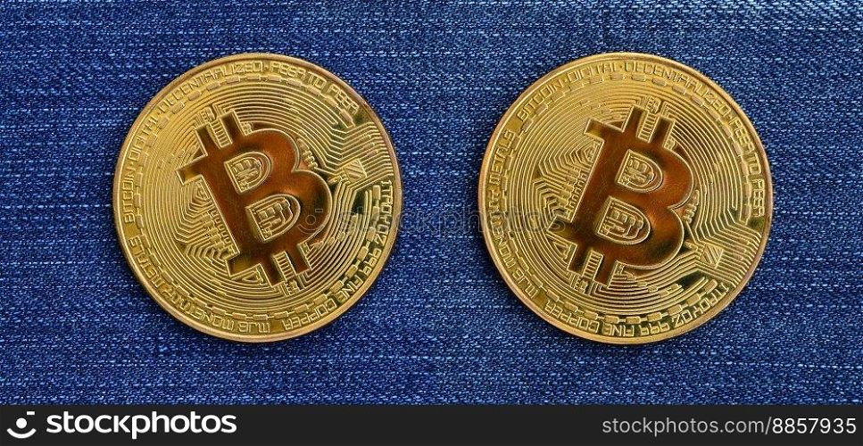 Two golden Bitcoins is lies on a blue jeans fabric. New virtual money. New crypto currency in the form of the coins