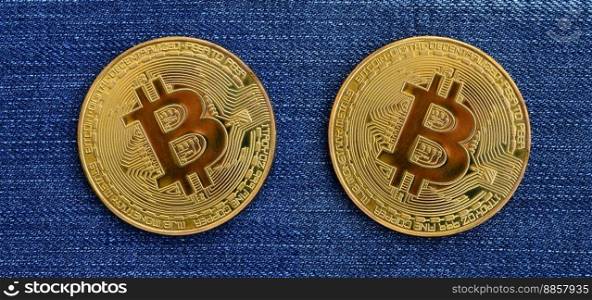 Two golden Bitcoins is lies on a blue jeans fabric. New virtual money. New crypto currency in the form of the coins