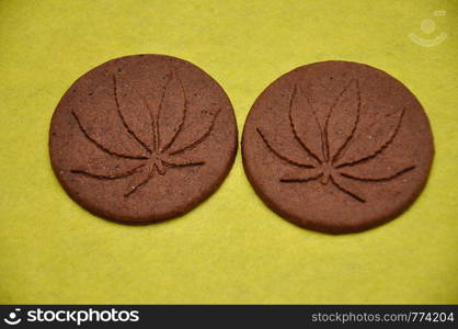 Two golden brown cannabis biscuits with cannabis leave prints