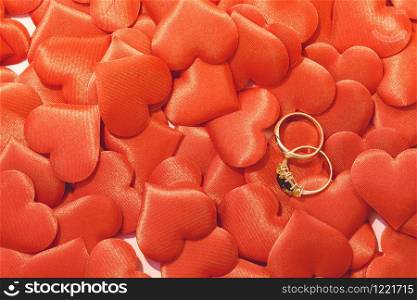 Two golden wedding rings on red satin hearts background. Love concept. Two golden wedding rings on red satin hearts background