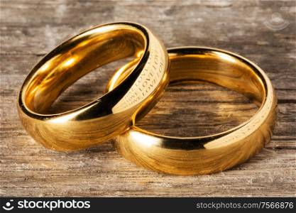 Two golden wedding rings on wooden background. Golden wedding rings on wood