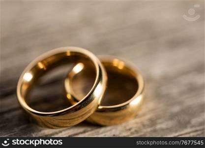 Two golden wedding rings on wooden background. Golden wedding rings on wood