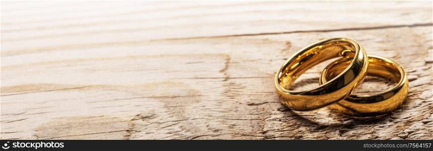 Two golden wedding rings on wooden background with copy space for text. Golden wedding rings on wood