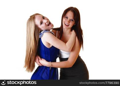 Two gorgeous young woman hugging each other and having fun in thestudio, laughing, with blond and brunette hair in a close picture.
