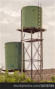 Two green water storage tanks . Two green water storage tanks on stilts in the savannah of Amboseli Park in Kenya