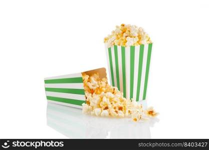 Two green white striped carton buckets with tasty cheese popcorn, isolated on white background. Box with scattering of popcorn grains. Movies, cinema and entertainment concept.