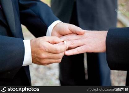 Two grooms exchanging rings at their wedding ceremony.