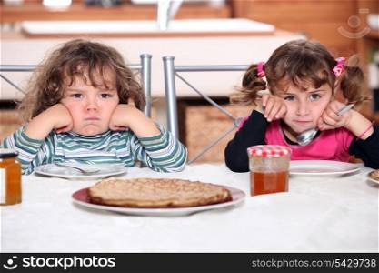 Two grumpy toddlers waiting for their pancakes