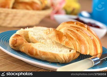 Two half croissants with strawberry jam in the back (Selective Focus, Focus on the front of the upper croissant half)