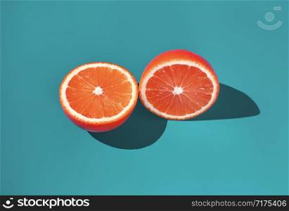 Two halves of ripe orange on a green background in bright sunlight .. Two halves of ripe orange on a green background in bright sunlight