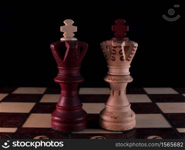 Two hand-decorated, wooden, chess kings are standing on a chessboard.. Two hand-decorated, wooden, chess kings