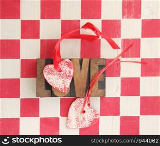 two handmade heart ornaments with the word &rsquo;love&rsquo; against a red checked background