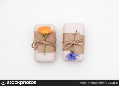 Two handmade natural soap decorated with craft paper with flowers on white background . Organic cosmetics concept. Top view Flat lay Copy space Template for design.. Two handmade natural soap decorated with craft paper with flowers on white background . Organic cosmetics concept. Top view Flat lay Copy space Template for design