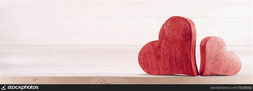 Two handmade red wooden carved hearts on light wood background couple relationship Valentine day concept. Two wooden hearts