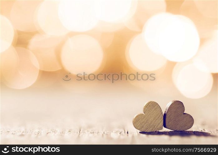 Two handmade wooden hearts on beautiful golden bokeh background. Vintage style. Love Valentine&rsquo;s Day concept.. Two hearts on bokeh background