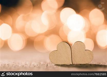 Two handmade wooden hearts on beautiful golden bokeh background. Vintage style. Love Valentine’s Day concept.. Two hearts on bokeh background