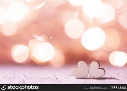 Two handmade wooden hearts on beautiful pink bokeh background. Vintage style. Love Valentine’s Day concept.. Two hearts on bokeh background