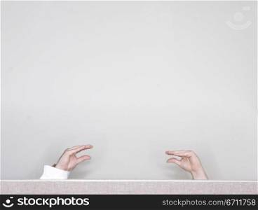 Two hands are talking to each other above a cubical wall with a white background