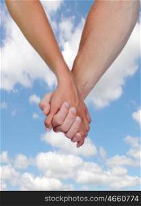 Two hands clasped in love with a blue sky background