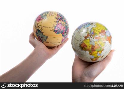 Two hands holding holding two globes in hand on white background