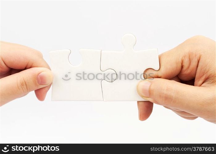 Two hands holding puzzle pieces and connecting them