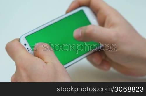 Two hands holding white smart phone, playing games greenscreen