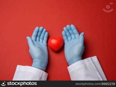 two hands in blue latex gloves holding a red heart, donation concept, top view
