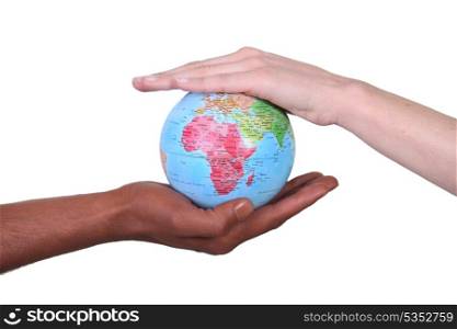 Two hands touching miniature globe