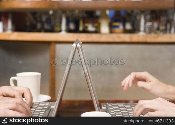 Two hands typing on laptops