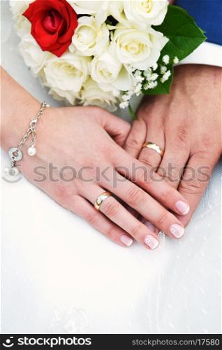 two hands with wedding rings and flowers