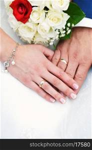 two hands with wedding rings and flowers