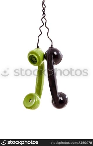 Two Handset piece from old phones suspended by the phone cord, isolated on white background