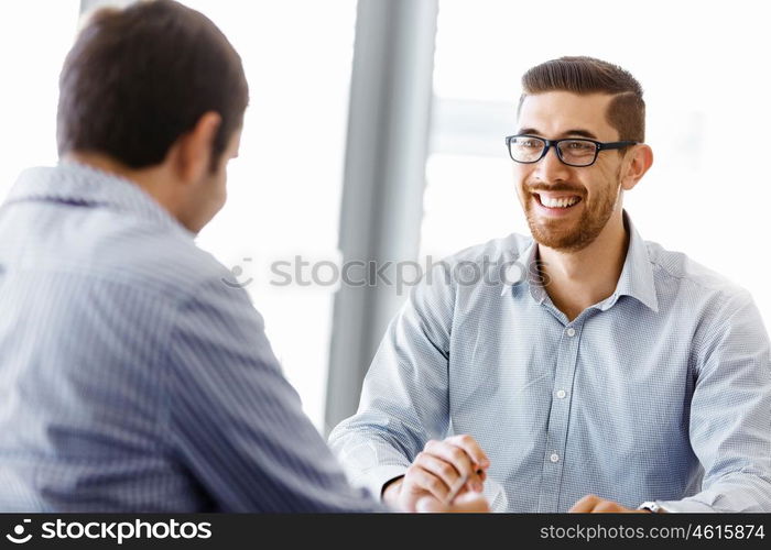 Two handsome businessmen in office. Two handsome businessman in office sitting at desk and talking