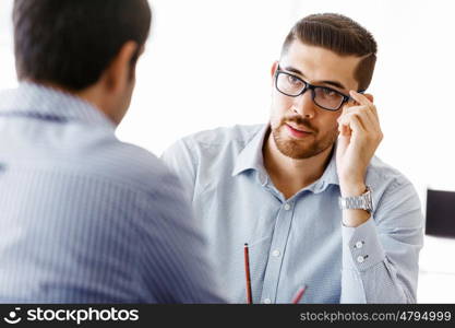 Two handsome businessmen in office. Two handsome businessman in office sitting at desk and talking