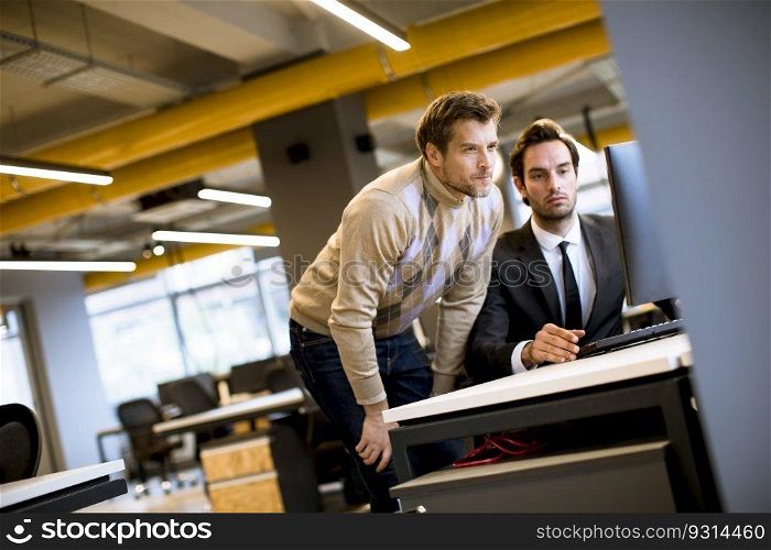 Two handsome young businessmen discussing in office by the table